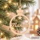 Bola de Navidad personalizada de madera con nombre Manuel, colgada con cuerda de yute en árbol de Navidad con luces decorativas. Adorno navideño de rotulaydecora.
