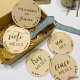 Cinco discos grabados al láser con algunos meses y la placa con el nombre de Jimena personalizado. Al fondo hay una caja de madera y un lazo azul.