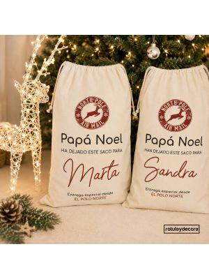 Sacos de Navidad personalizados para regalos de Papá Noel, de tela beige con cierre de cordón, sello del Polo Norte y nombres Marta y Sandra en rojo.